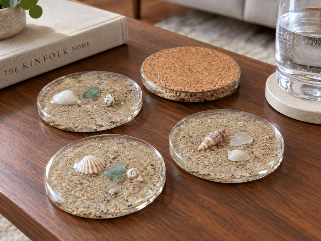 Round resin coasters with beach sand, small shells and sea glass sealed inside, set on a wooden coffee table