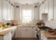 A bright, modern small L-shaped kitchen featuring floor-to-ceiling white cabinets, light oak wood countertops, and a clear, organized meal prep area.