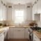 A bright, modern small L-shaped kitchen featuring floor-to-ceiling white cabinets, light oak wood countertops, and a clear, organized meal prep area.