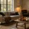 A sunlit, cozy living room styled for autumn with a cream sofa, camel bouclé throw, moss green velvet pillows, aged brass decor, and tall branches in a ceramic urn.
