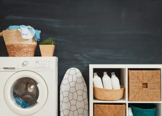 Organized small laundry closet with floating wooden shelves and clear detergent jars above stacked machines