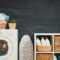 Organized small laundry closet with floating wooden shelves and clear detergent jars above stacked machines