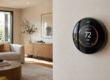 Google Nest Learning Thermostat 4th Gen mounted on a white living room wall with temperature display