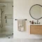 Bright bathroom with a black towel bar by the shower door, a folded bath towel and a hand towel ring near the mirror
